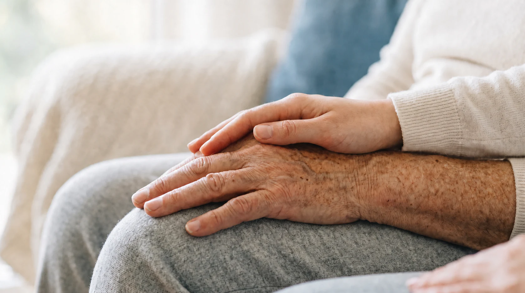 One person resting a reassuring hand over another person's hands